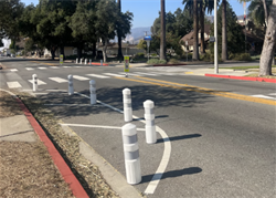 Image of a new project at Minnesota Avenue with a newly installed crosswalk with white poles and yellow crosswalk signs aiding pedestrian traffic